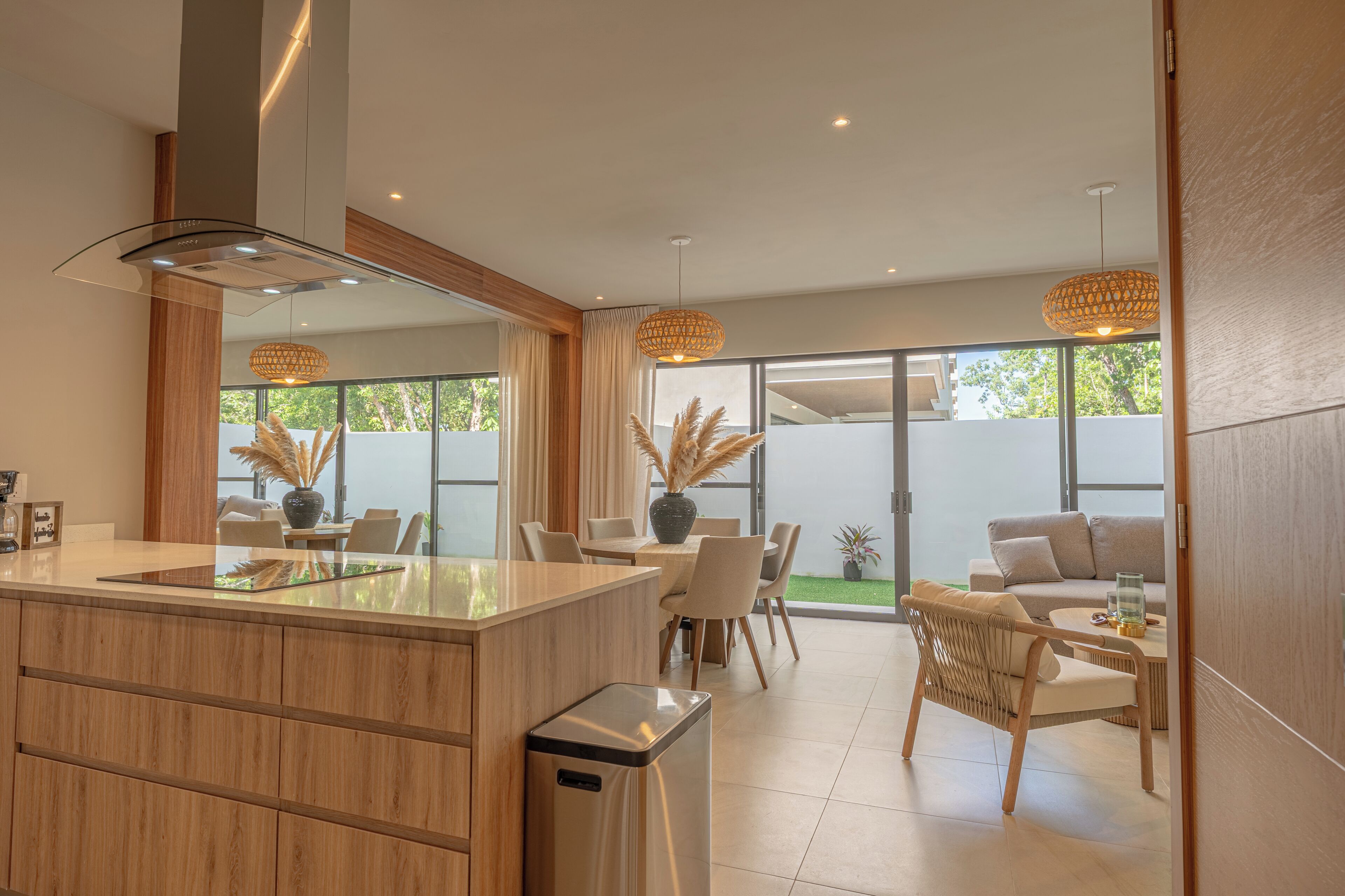 A modern kitchen with a central island, dining area with chairs, and a sofa.