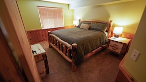 Un dormitorio con una cama de madera, una mesita de noche, una lámpara y una ventana con persianas.