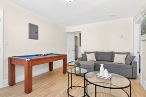 Ein Zimmer mit Poolbillard, einer Couch und einem Glastisch.