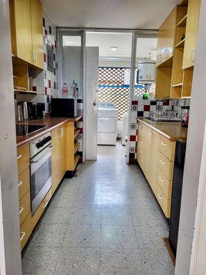 A kitchen with wooden cabinets, stainless steel appliances, and a tiled backsplash. - Apartment 3 Bedrooms | 1 block from Larcomar and Marriott (Miraflores)