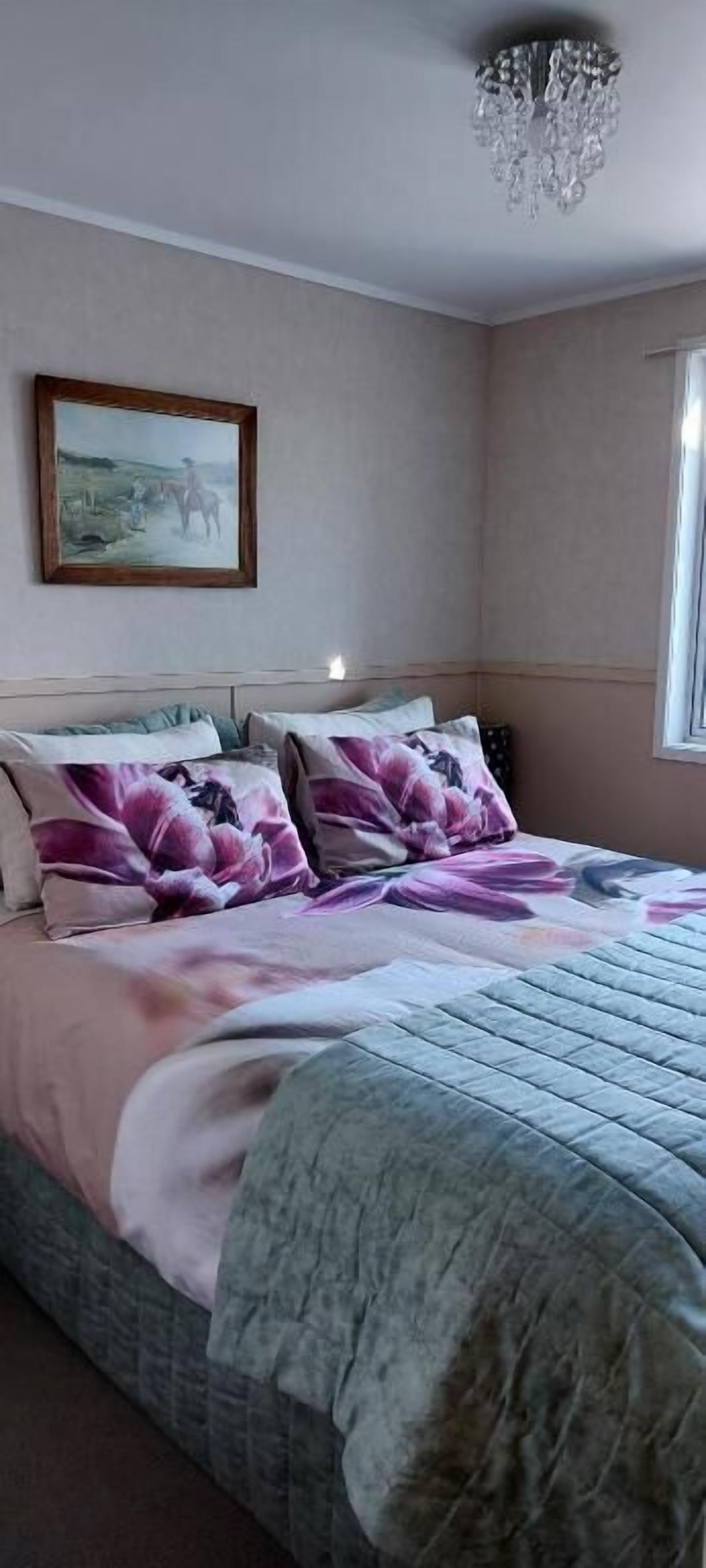 Un dormitorio con cama, candelabro, un cuadro enmarcado y ventana.
