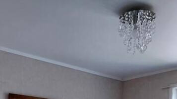Un dormitorio con cama, candelabro, un cuadro enmarcado y ventana.