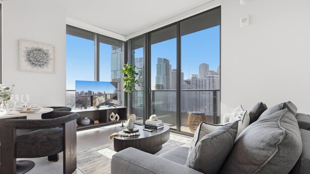 A modern living room with a sofa, a coffee table, and a dining area with chairs and a table. - 501 First Amazing Corner OceanView Rooftop Pool & GYM 2901 (Miami)