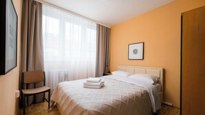 A hotel room with a bed, a chair, a bedside table, and a framed picture on the wall. - Royal Baths Spacious Apartment (Warszawa)
