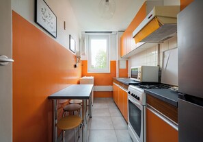 Una cocina con paredes anaranjadas, una ventana, una estufa y un microondas.
