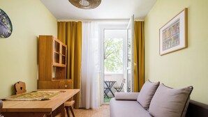 A room with a wooden dining table, a sofa, a cabinet, and a door leading to an outdoor area. - Royal Baths Spacious Apartment (Warszawa)