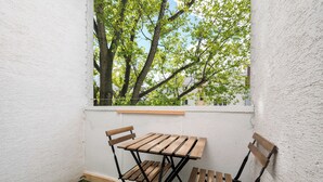 A small room with a wooden table and chairs, a window with a view of trees, and a green artificial turf floor. - Royal Baths Spacious Apartment (Warszawa)
