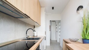 A modern kitchen with a black induction cooktop, wooden cabinets, and a white countertop.