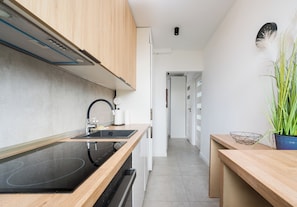 Una cocina moderna con placa de inducción negra, armarios de madera y encimera blanca.