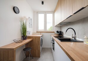A compact kitchen with a washing machine, a sink, and a window. - Metro Kondratowicza Stylish Apartment (Warszawa)