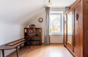 Une pièce avec un bureau en bois, des étagères, une grande fenêtre avec des rideaux et une armoire.