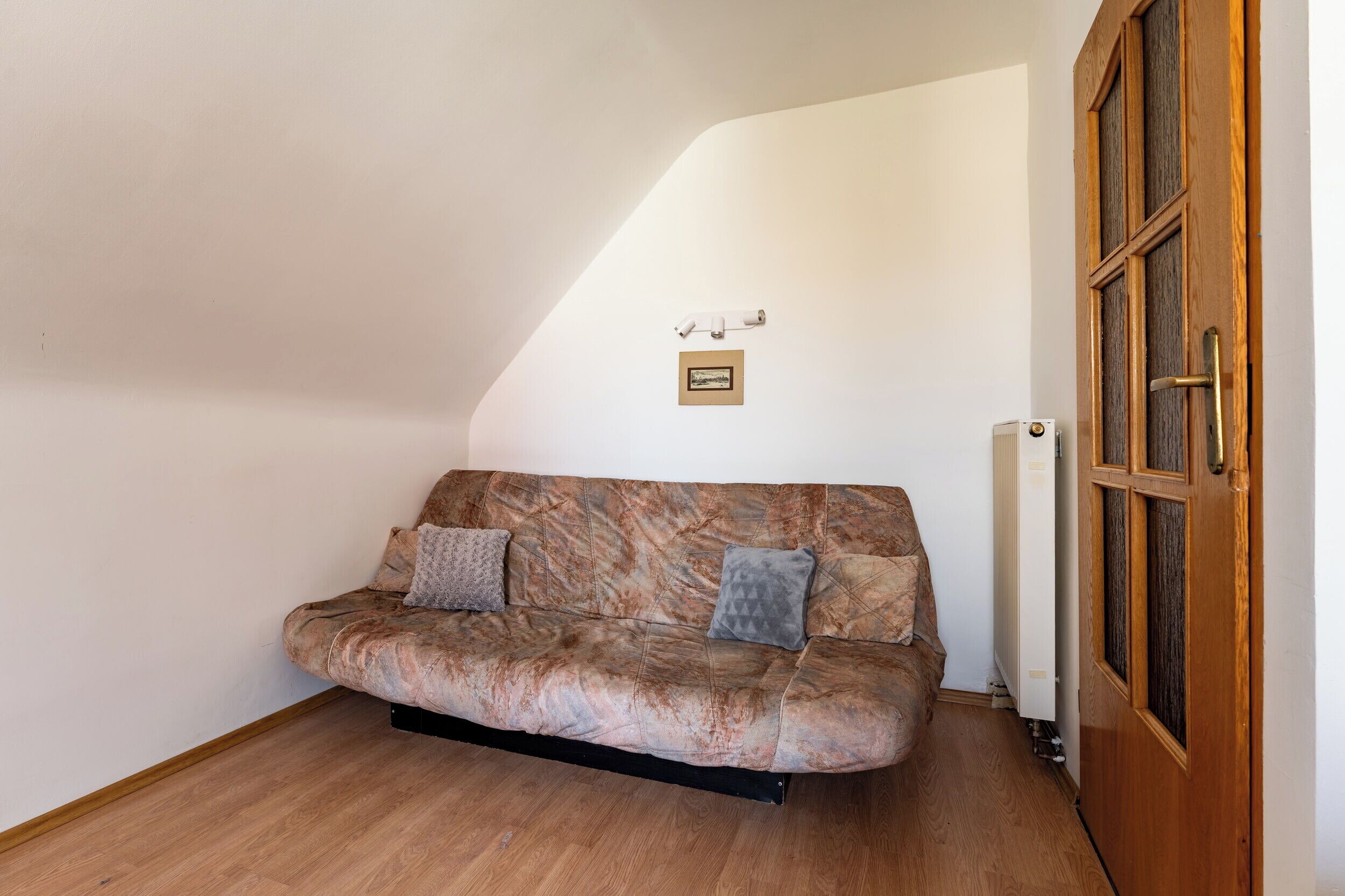 A room with a sofa, a radiator, and a wooden door.