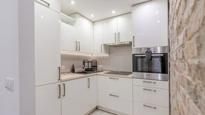 Una cucina moderna con mobili bianchi, un forno Bosch e un muro in pietra.