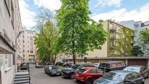 A parking lot with multiple cars, a tree, and residential buildings in the background. - Tamka Powiśle Superior Studio (Warszawa)