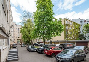 A parking lot with multiple cars, a tree, and residential buildings in the background. - Tamka Powiśle Superior Studio (Warszawa)