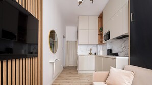 A modern kitchen with wooden cabinetry, a marble backsplash, and a built-in oven. - Tamka Powiśle Superior Studio (Warszawa)