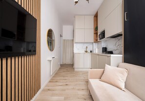 A modern kitchen with wooden cabinetry, a marble backsplash, and a built-in oven. - Tamka Powiśle Superior Studio (Warszawa)
