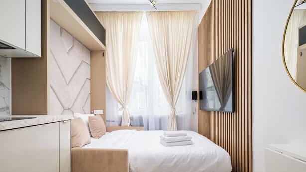 A modern hotel room with a bed, a desk, a chair, a TV, and a window with curtains. - Tamka Powiśle Superior Studio (Warszawa)