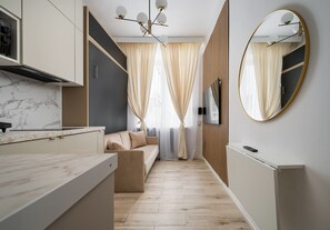 A modern kitchen with a marble countertop, a built-in oven, and a wall-mounted TV. - Tamka Powiśle Superior Studio (Warszawa)