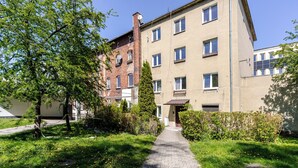 Ein mehrstöckiges Gebäude mit einer Ziegel-Fassade, einem gepflasterten Weg und umgebender Bepflanzung.