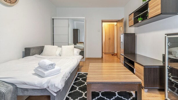 Ein modernes Hotelzimmer mit Bett, Nachttisch, Kleiderschrank und Spiegel.