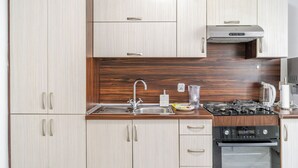Eine moderne Küche mit hellen Holzschränken, Edelstahlgeräten und einem eingebauten Backofen.