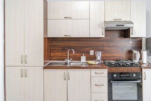 Eine moderne Küche mit hellen Holzschränken, Edelstahlgeräten und einem eingebauten Backofen.