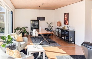 A modern living room with a dining area, wooden ceiling, and large windows. - 4 bedroom cozy home in Allinge (Allinge)