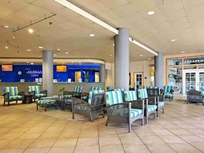 Eine Lobby mit Korbsesseln, einem Empfangstresen und einem Café.