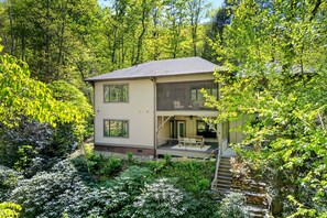 A two-story house with a balcony, surrounded by dense greenery. - Brookside Retreat | Elegant 3BR Home 5 Min. from Downtown Black Mtn! (Black Mountain)