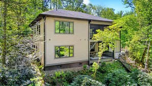 Een huis met twee verdiepingen, een overdekte veranda en een kleine trap naar een hoger gelegen niveau.