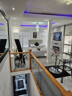Una habitación de hotel moderna con cama, televisión, una mesa de vidrio y un balcón.