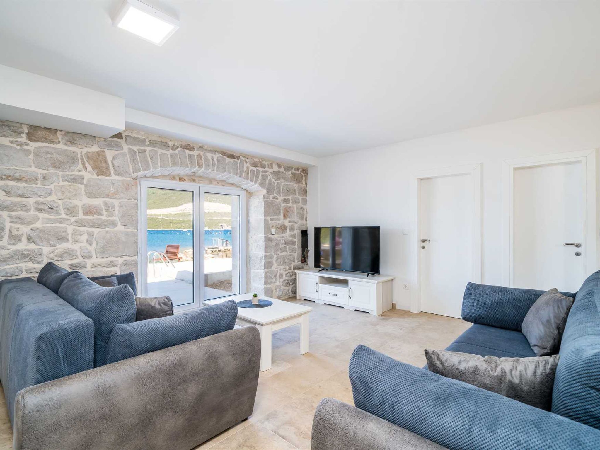 A living room with stone walls, a television, and two sofas.
