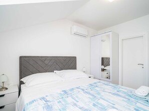 Une chambre d’hôtel comprenant un lit, une table de chevet, une lampe, un appareil de climatisation, une armoire et une porte.