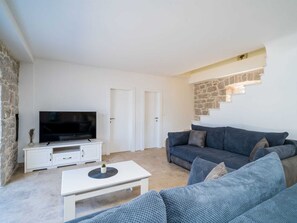 A living room with a flat-screen TV, a white entertainment unit, a grey sofa, and a staircase with stone accents. - Beachfront Villa Olive Mill with pool by Interhome (Putniković)