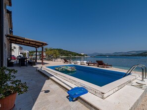 A pool with lounge chairs, a pergola, and a view of the sea. - Beachfront Villa Olive Mill with pool by Interhome (Putniković)