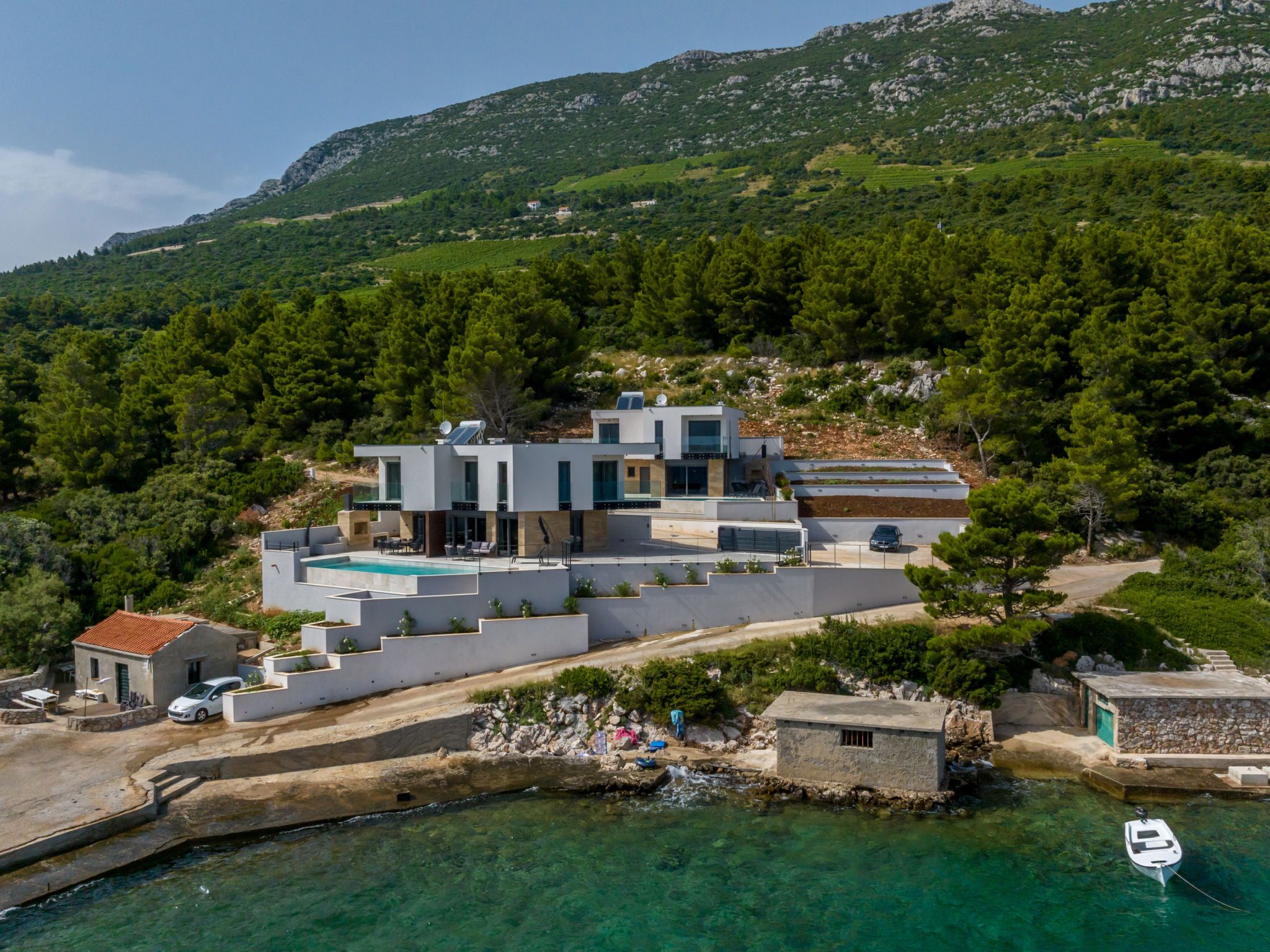 Una villa moderna con piscina, cerca de un cuerpo de agua con un barco amarrado.