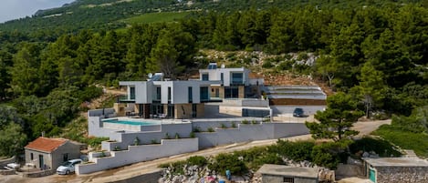 Una villa moderna con piscina, cerca de un cuerpo de agua con un barco amarrado.