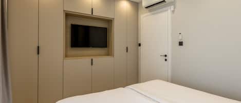 Une chambre à coucher avec un lit, une armoire et un téléviseur intégré.