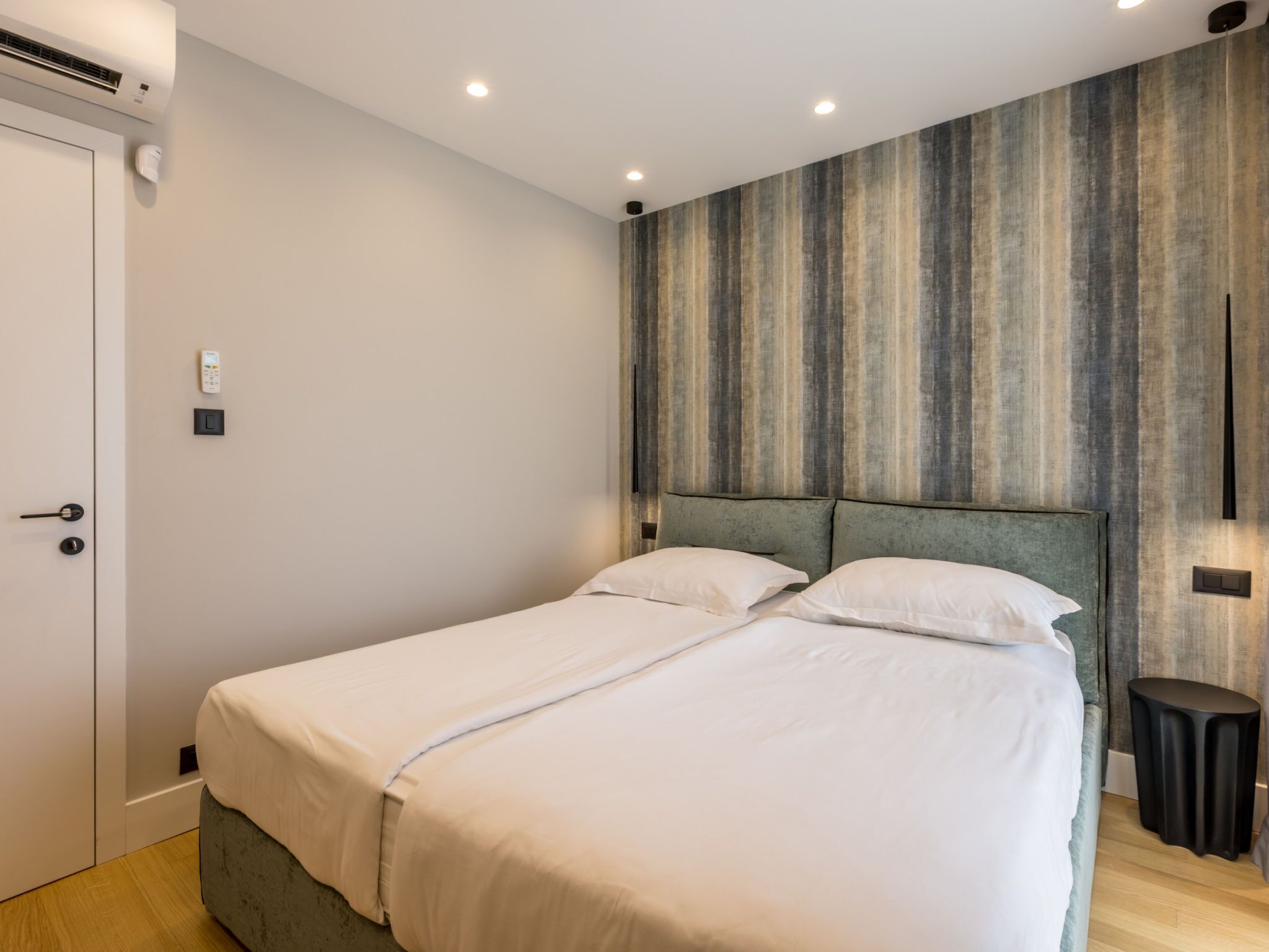 Un letto matrimoniale con testiera, un comodino e una lampada a parete.