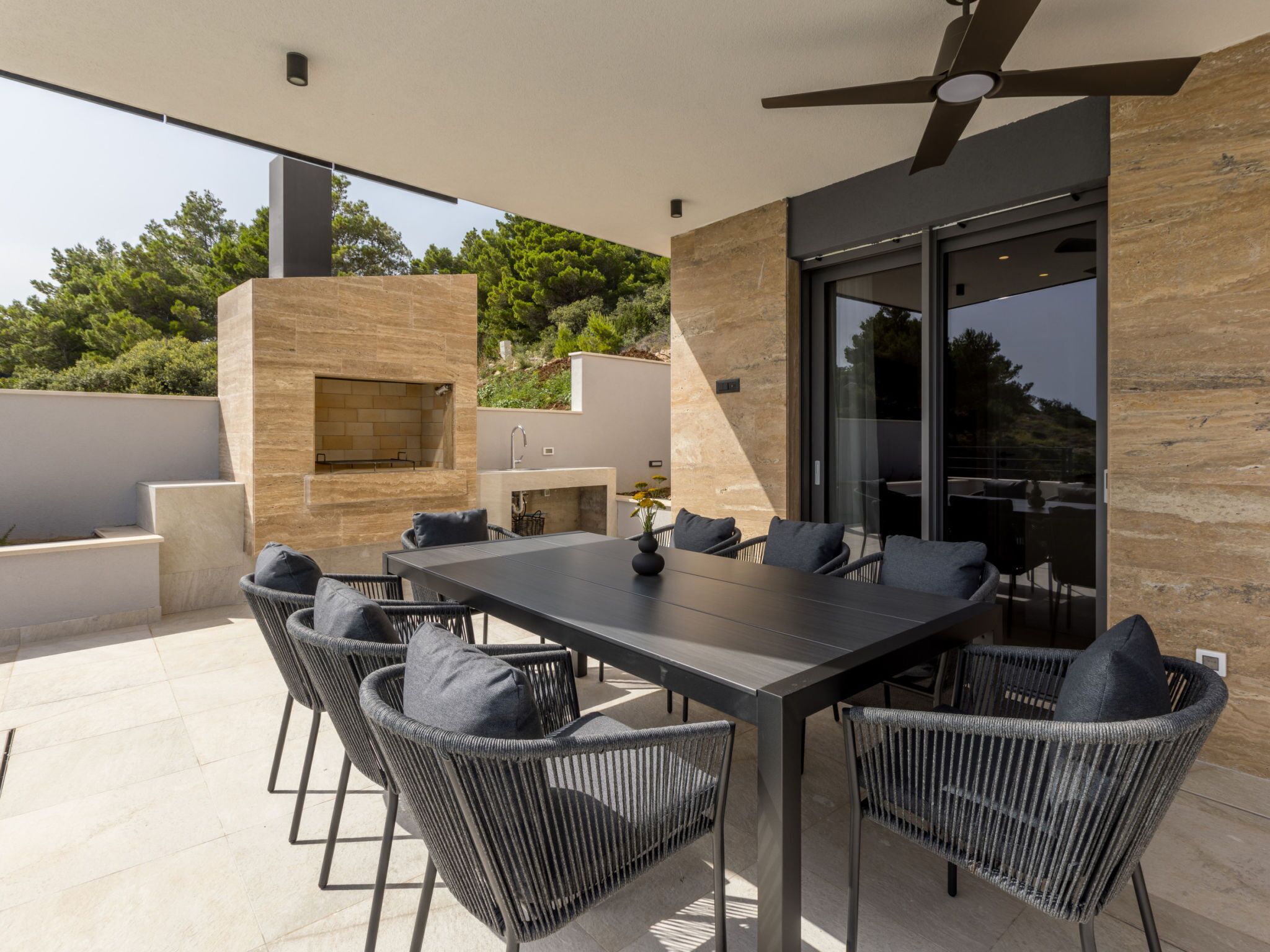 Eine Terrasse im Freien mit Esstisch, Stühlen und einem eingebauten Grill.