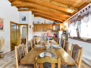 Ein Esszimmer mit einem Holztisch, gedeckt für sechs Personen, umgeben von Holzstühlen.