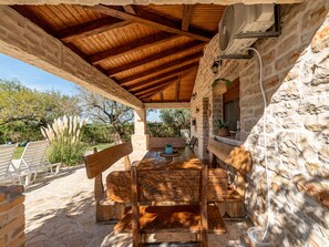 Une terrasse extérieure avec des murs en pierre, des bancs en bois et une table.