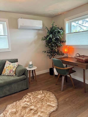 A living room with a sofa, a small table, a chair, a lamp, a potted plant, and a rug.