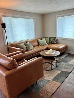 A living room with a brown leather sofa, a round coffee table, and a floor lamp.