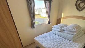 Une chambre à coucher avec un lit, des rideaux, une fenêtre et une vue sur un bâtiment à l’extérieur.