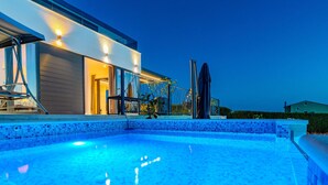 Ein modernes Haus mit Swimmingpool im Abenddämmerung.