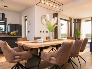 A modern dining area with a wooden table, brown upholstered chairs, and a decorative vase with white feathers. - Beautiful villa Lara in Vrana with pool by Interhome (Drage)