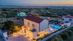 Eine moderne Villa mit Swimmingpool, umgeben von einem angelegten Garten und Blick ins Grüne.