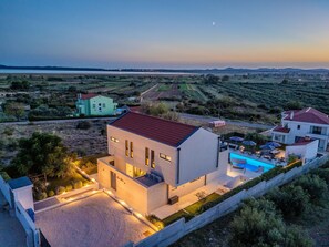 A modern villa with a swimming pool, surrounded by a landscaped garden and a view of the countryside. - Beautiful villa Lara in Vrana with pool by Interhome (Drage)